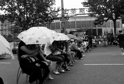 天太热，业主们打着伞坐着凳子等待房地产商的回话.jpg